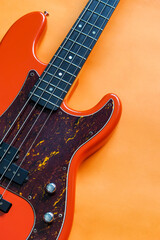 Obraz na płótnie Canvas orange electric bass guitar on orange background with copy space