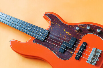 orange electric bass guitar on orange background with copy space - obrazy, fototapety, plakaty
