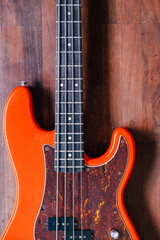 Fototapeta premium orange electric bass guitar on wood background with copy space