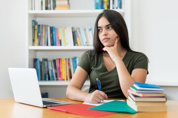 Thinking spanish female student at desk