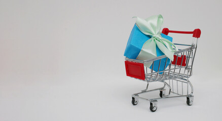 Christmas decorative gift blue box in a mini shopping trolley on a white background.