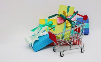 Shopping cart and four multi-colored gift boxes on a white background.