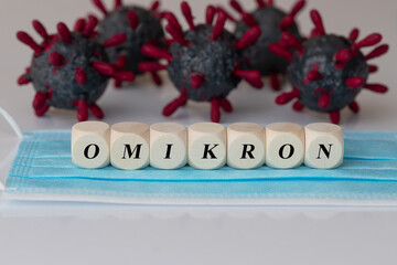 the word Omikron on wooden cubes, with virus models in the Background. Omikron is the new type of...