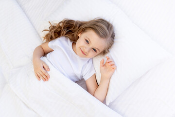 cute baby girl sleeping on a bed on a white cotton pillow under a blanket, healthy baby sleep at...