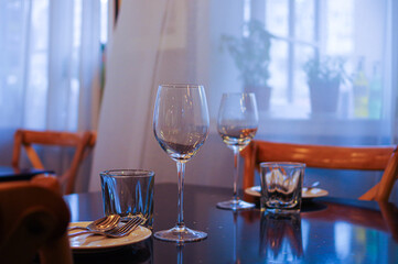 table setting in empty restaurant with clean wine glasses and cutlery on black table	