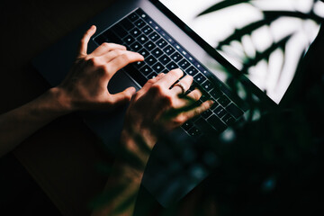 Woman typing on laptop keyboard at the night, close-up.