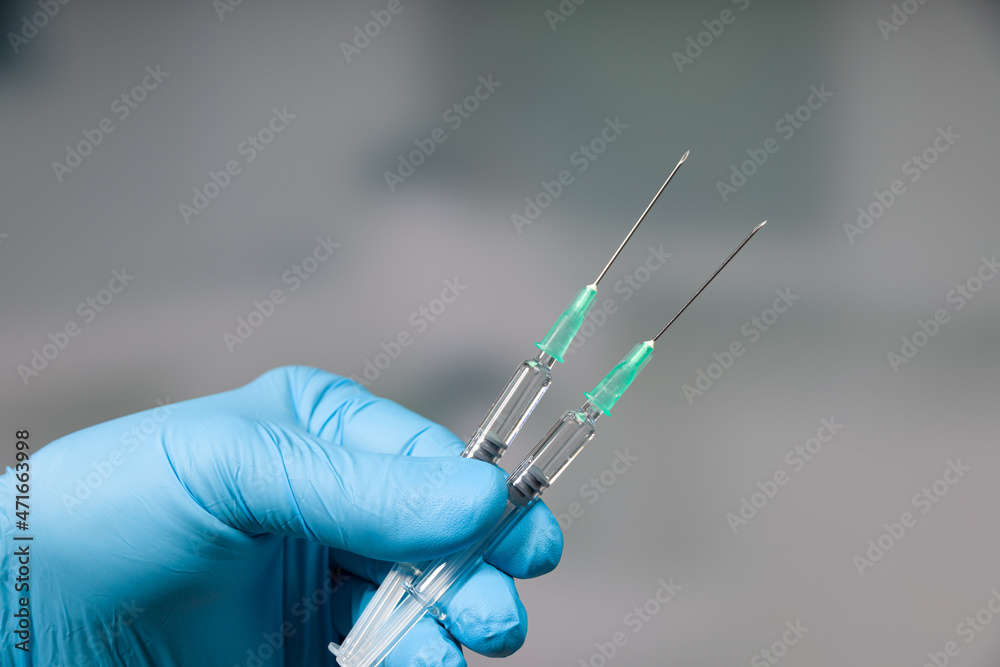 Wall mural close up of doctor's hand in medical gloves with two syringes ready for coronavirus injection