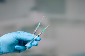 Close up of doctor's hand in medical gloves with two syringes ready for coronavirus injection
