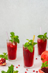 Refreshing pomegranate juice in glasses with mint and glass straw, cold drink