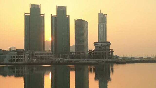 Sunrise at Al Reem island in Abu Dhabi, cityscape. Silhouettes of the high rise modern buildings with sun rising behind them.