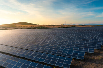 Aerial close up view of large solar panels at a solar farm at summer evening.