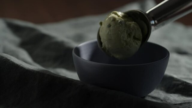 Slow motion put a ball of pistachio ice cream into small blue bowl