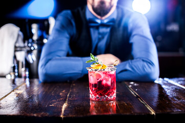 Professional barman creates a cocktail while standing near the bar counter in bar