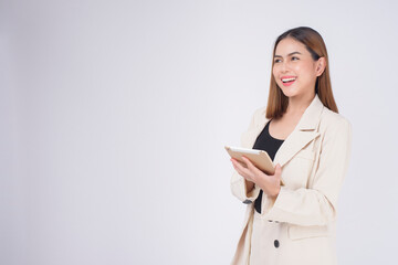 Young beautiful businesswoman in suit holding tablet over white Studio background.