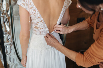 Obraz na płótnie Canvas Bride putting on a beautiful white wedding dress