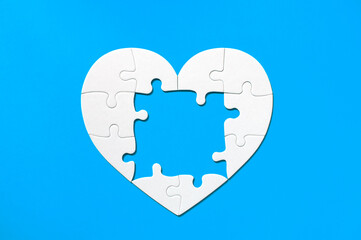 Puzzle pieces on blue background. White heart puzzle pieces grid. Healthcare concept. Copy space for text, top view, close up.