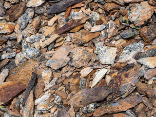 Layered detailed texture of a rocky mountain slope. Geological scattering of stones in close-up. Nature background of chaotic pile of stones. Minimalist texture of stony heap