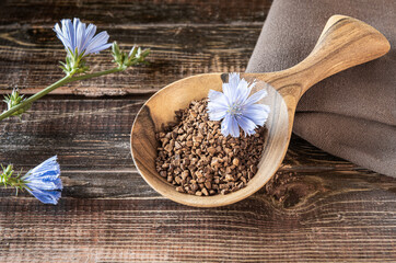 Flowers and Instant granules of chicory on wooden background