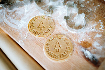 Gingerbread christmas cookies cutters and rolling pin over wooden pastry board