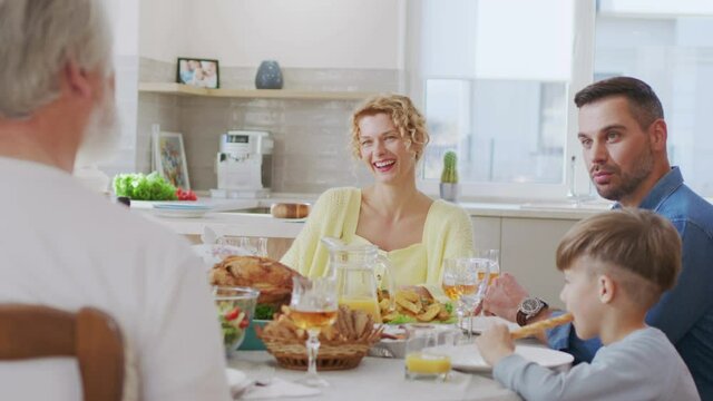 Caucasian family gathering together and chatting. Happy man telling something to his senior father while sitting at the table and spending time with family