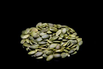 Peeled pumpkin seeds on black background