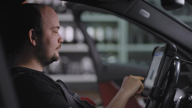 Close up: Using Digital Tablet For A Car Diagnostic. mechanic using a tablet pc at the repair garage service. Interactive Diagnostics Software on an Advanced Computer.