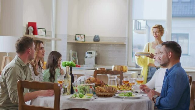 Caucasian family gathering together and chatting. Happy bringing tasty pie at the table while spending time with her family