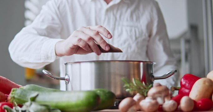 the chef adds spices and salt to the cooking dish in a metal saucepan.