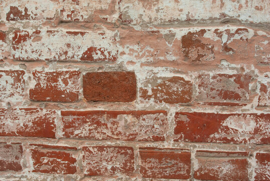 View of red brick weathered wall covered with white paint. Copyspace. Closeup