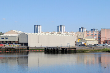 Fototapeta na wymiar River View of Riverside Industrial Buildings seen against Blue Sky 