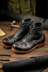 Hand crafted black leather high boots on wooden background