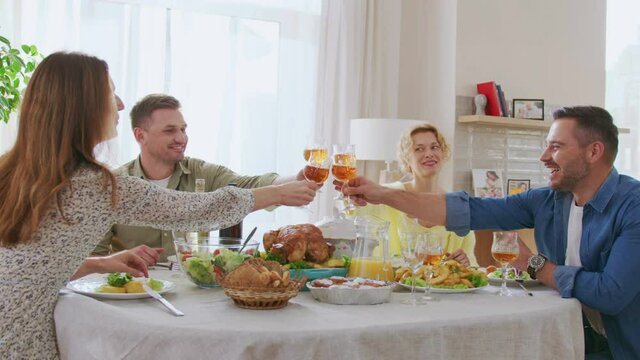 Happy family time and relationship. Waist up portrait view of the best friends having party, eating food and toasting wine glass together at home. People enjoy eating meal on dining table at home
