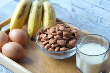 eggs in a plastic container, milk and almond nut in table 