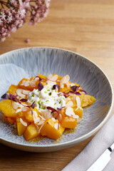 baked pumpkin in ceramic plate on wooden table. pumpkin with stracciatella and microgreen