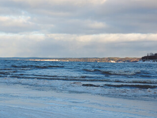 Late autumn on the beach. There are waves on the Kama river. The shore is icy. Russia, Ural, Perm region.