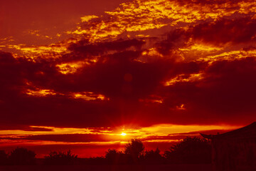 Obraz premium Setting sun make rays through the cloudy red sky