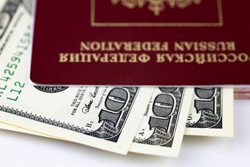 The Russian passport contains American 100 dollar bills. Close up, selective focus, white background. 
