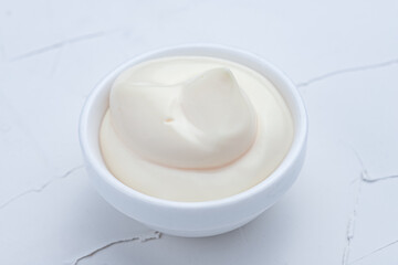 mayonnaise, homemade mayonnaise in a saucepan on a white background, concrete background