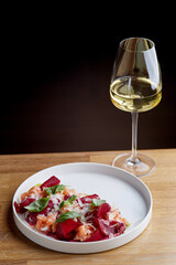 salmon salad with beet cheese and green leaves on wooden table with glass of white wine.