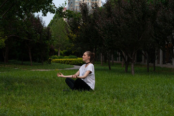Naklejka na ściany i meble Young woman doing yoga in the park