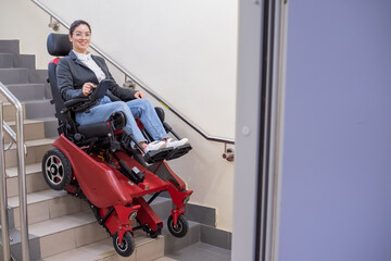 Caucasian woman in electric caterpillar wheelchair climbs up stairs.