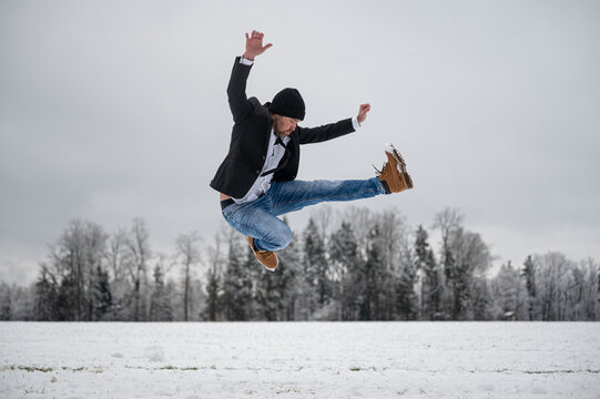 Cheerful young man jumping with joy outside in white snowy nature