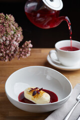 cheesecake with berry sauce and pouring red tea on background. breakfast morning table with flowers. cottage cheese pancakes.