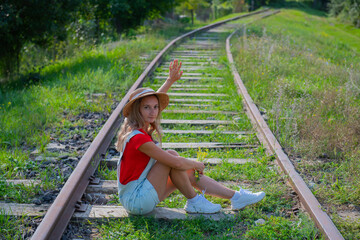 tourist waving his hand in overalls sitting on the railroad