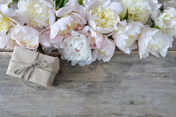 Beautiful celebration background; frame of white peonies and handmade gift box on old wooden background; copy space,