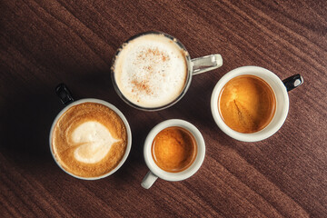 Cups of coffee in the hands of men and women. coffee break on a wooden background. with copy space. top view