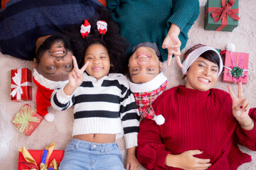 Happy African family lying smiling on Christmas day together while gift box on floor, top view, relationship and bonding of family, celebration and holiday, new year and xmas, fun and cozy.