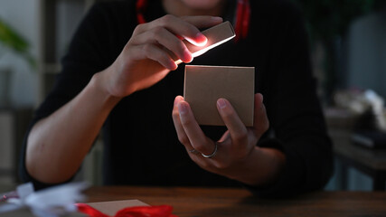 Cropped image of a man opening a present box with gold light means something exciting inside.