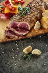 Grilled beef steak fillet with ingredients and herbs on black board, product image for restaurant