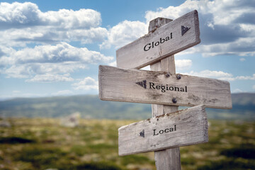 global regional local text quote on wooden signpost outdoors in nature. Blue sky above. - obrazy, fototapety, plakaty